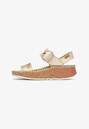 Beige platform sandals with a cork base, metallic gold accent on the toe, and a wide strap featuring a round buckle detail.