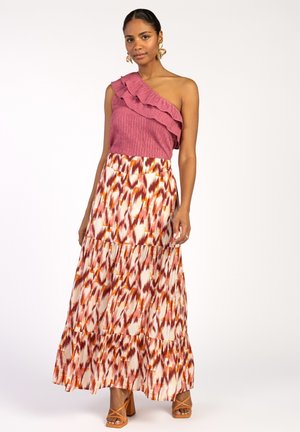 Fuchsia top met één schouder en ruches, gecombineerd met een lange, gestreepte rok in roomwit, rood en oranje. Sandalen met hoge hakken in lichtbruin met bandjes.