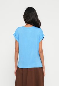 Modré tričko s krátkými rukávy vyrobené z lehké tkaniny, s volnějším střihem, kulatým výstřihem a olemováním s ohrnutými manžetami.