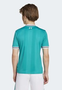Tirkizna sportska majica s vertikalnim prugama, kratkim rukavima i bijelim prugastim ovratnikom. Sadrži logotip i mali broj na leđima.