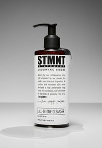 Flacon pompe en plastique ambré foncé avec une pompe noire. L'étiquette présente une typographie audacieuse sur fond blanc, indiquant "NETTOYANT TOUT-EN-UN" ainsi que la description du produit.