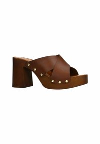 Mules en cuir brun avec plateforme, design à lanières croisées, accents en clous dorés et un talon épais. Texture lisse et style ouvert à l'avant.