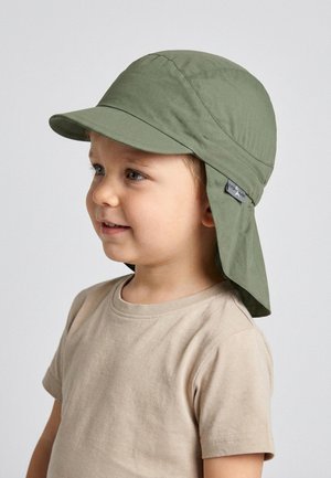 Young child wearing a beige shirt and an olive green sun hat with a neck flap, looking slightly to the left against a plain background.