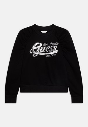 Czarna bluza z długim rękawem, z falbaniastymi ramionami i błyszczącym, srebrnym napisem z cekinów "Guess Los Angeles Est. 1981" z przodu.