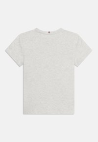 Ανοιχτό γκρι κοντομάνικο μπλουζάκι με μια μικρή κόκκινη, λευκή και μπλε ριγέ ετικέτα στο πίσω μέρος του λαιμού, που φαίνεται από την πίσω πλευρά.