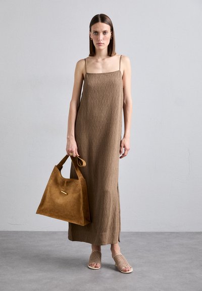 Brun kjole uten ermer med strukturert stoff, kombinert med en sandfarget semsket skinnveske og flettede sandaler. Enkel design med sidelommer for bevegelighet.