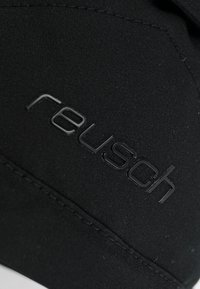 Guanti sportivi neri realizzati con un tessuto liscio e elastico. Presentano il logo "reusch" in rilievo, cuciture prominenti lungo i bordi e nessun motivo visibile.