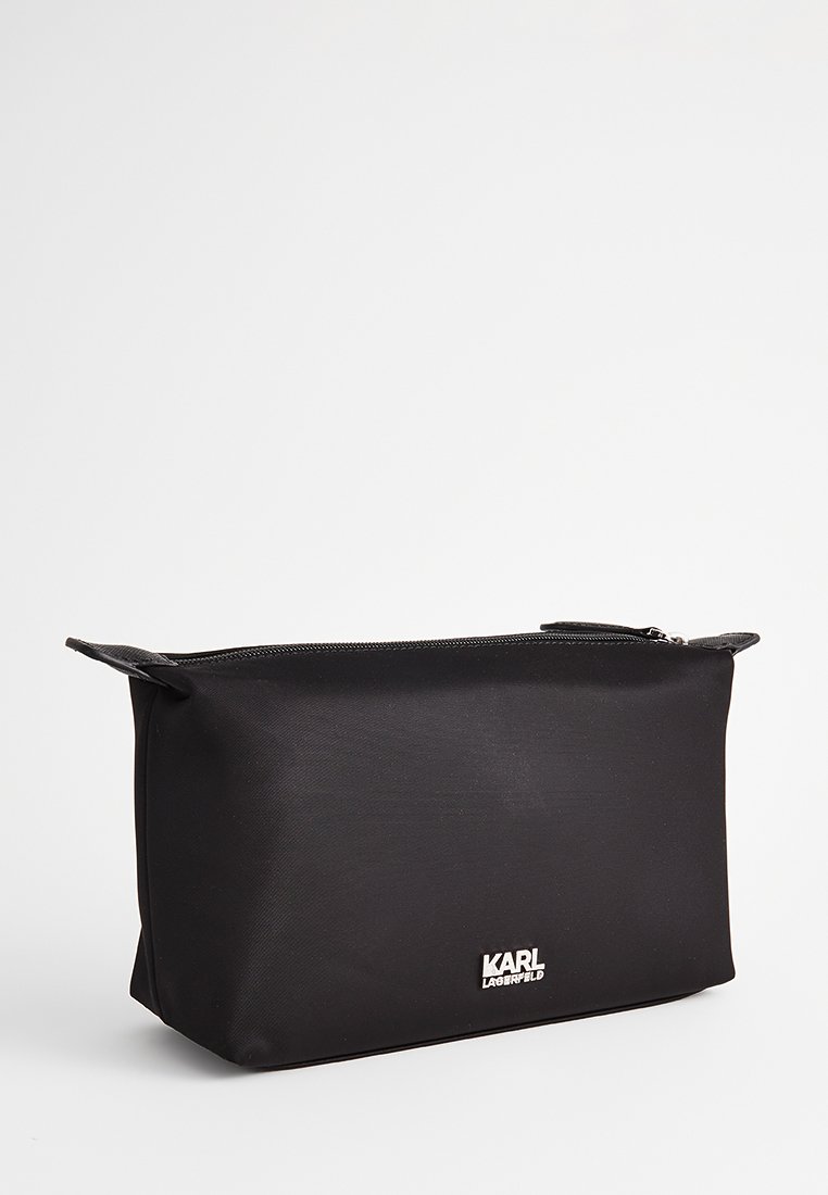 Borsa da toilette nera realizzata in materiale resistente, con chiusura a zip, forma piatta e logo argentato sul davanti. Design compatto.