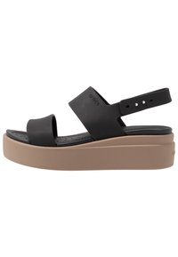 Schwarze Plateausandalen mit zwei breiten Riemen und einem verstellbaren Knöchelriemen. Texturiertes Fußbett und beige Grundlage. Gummi-Material.