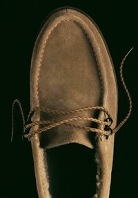 Scarpa in camoscio marrone con punta arrotondata, caratterizzata da cuciture testurizzate, lacci marroni e una morbida fodera interna, mostrata da una vista dall'alto.