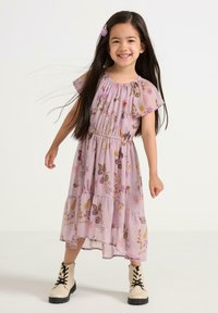 Lavendelfärgad blommig klänning med korta fladdrande ärmar, lager-på-lager-design och resår i midjan; kombinerad med beige snörstövletter.