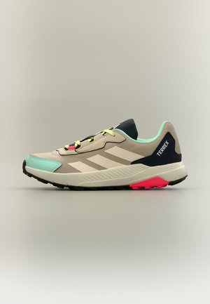 Beež ja mündi roheline Adidas Terrex tennisejalanõu mustade ja punaste tallatutvustustega, külgmiste triipude ja kollaste paeltega, külgvaade neutraalsel taustal.