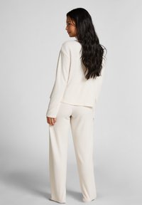 Geribbelde loungewear set in lichtbeige, bestaande uit een relaxed-fit langemouwen top en hoge taille broek met een rechte pijp.