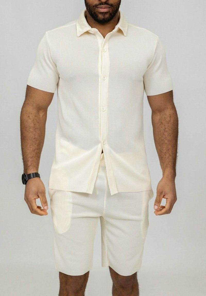 Chemise à manches courtes côtelée de couleur beige clair avec un devant boutonné et un col, associée à un short côtelé assorti, doté de poches latérales.