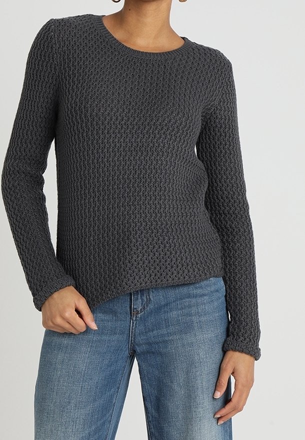 Grijze gebreide sweater met textuur, lange mouwen, ronde halslijn en een relaxte pasvorm, gecombineerd met blauwe jeans.