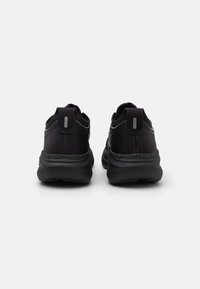 Black athletic shoes with a textured upper, featuring a pull tab, subtle branding, and a cushioned sole for added comfort and support.