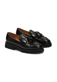 Black leather loafers with a chunky black outsole, featuring a decorative tasseled front and a smooth finish.