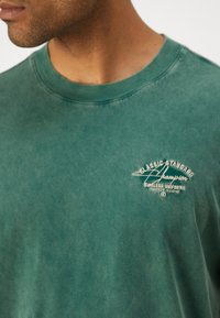 Champion ICONS WASH CREWNECK WITH GRAPHICS - T-shirts print - dark green