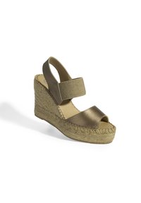 Sandale en bronze métallique à talon compensé, avec une ouverture à l'avant, une sangle élastique à la cheville et un détail en jute tissé sur la plateforme. Texture lisse et design structuré.