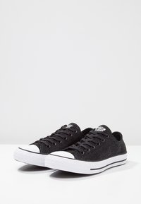 Sneaker nere in tela con finitura testurizzata, suola in gomma bianca e punta rinforzata, con lacci neri e logo classico sulla linguetta.