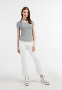 Grå, ribbet t-shirt med en snøre detalje ved halsen, sammen med hvide, cropped jeans og multicolore, høj-top sneakers med en struktureret finish.
