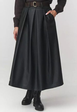 Czarna spódnica maxi z ekoskóry z plisami, brązowy pasek z złotą klamrą i bocznymi kieszeniami. Noszona z czarnymi botkami na sznurówki.