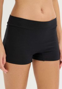 Shorts neri elasticizzati con una cintura ampia, caratterizzati da una texture liscia e un design aderente, ideali per l'abbigliamento attivo o per un uso casual.