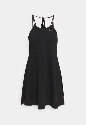 Black sleeveless dress with thin straps, cinched tie at the back, and a flared skirt. Notable pom-pom hem detail and small branded tag on the side.