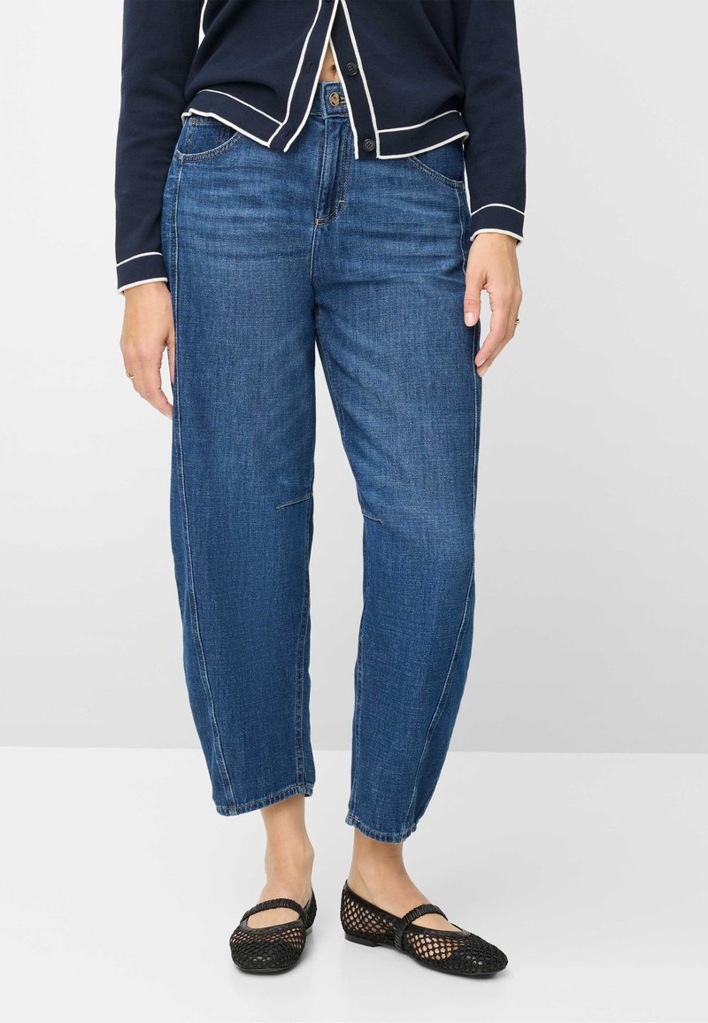 Denimjeans i en medium blå nuance med en afslappet pasform, der har lige ben og en subtil falmet tekstur. Kombineret med sorte mesh-ballerinasko.