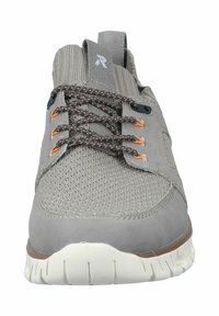 Zapatilla deportiva gris con parte superior de tejido texturizado, acentos de ante, cordones marrones y suela de goma blanca. Presenta una etiqueta de lazo en el talón.