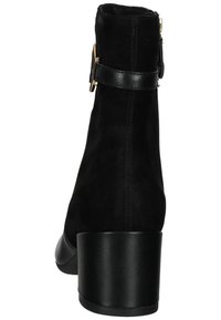 Stivale alla caviglia in suede nero con tacco spesso nero, dotato di un dettaglio con fibbia laterale e una fascetta in pelle liscia. Vista posteriore che mostra le cuciture.