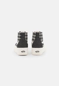 Hoge sneakers van donkergrijs stof met een wit ruitpatroon, met een dikke witte zool en een logo op de hiel.