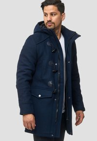 Parka de mezcla de lana azul marino con cierre de cremallera y cierres de toggle, que cuenta con una gran capucha y bolsillos laterales para mayor funcionalidad.