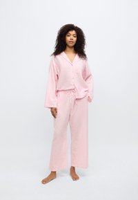 Σετ πιτζάμες ροζ καρό με μακριά μανίκια και ελαστική μέση με κορδόνι. Μαλακό, ελαφρύ ύφασμα με άνετη εφαρμογή και κουμπιά στο μπροστινό μέρος.