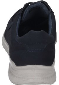 Scarpa sportiva blu navy con una parte superiore testurizzata, colletto imbottito e suola in gomma. Foderatura grigia a contrasto visibile dalla vista posteriore.