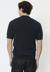 Pull en maille bleu marine à manches courtes avec un motif texturé, poignets et ourlet côtelés. Design légèrement respirant.