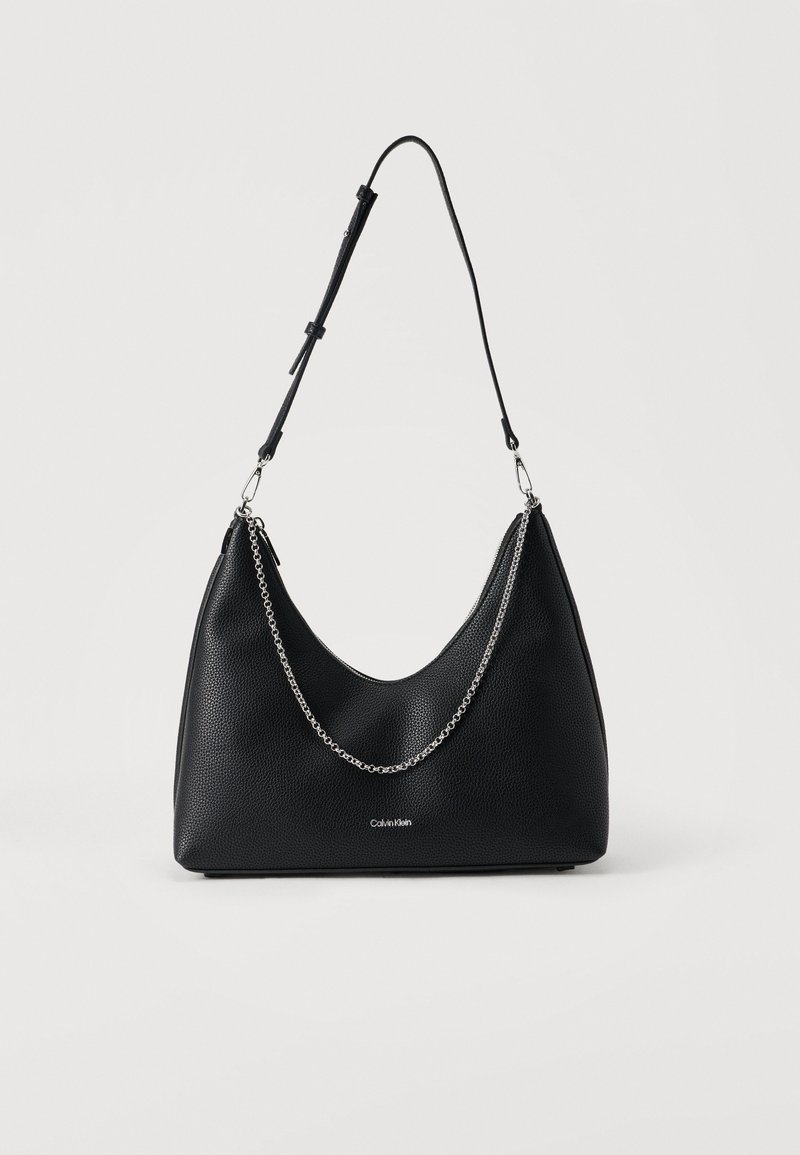 Μαύρη τσάντα χειρός από δέρμα με κοκκώδη υφή σε σχήμα ημισελήνου, με ασημί αλυσίδα ως διακοσμητικό και ρυθμιζόμενο λουράκι. Διαθέτει λογότυπο στο μπροστινό μέρος.