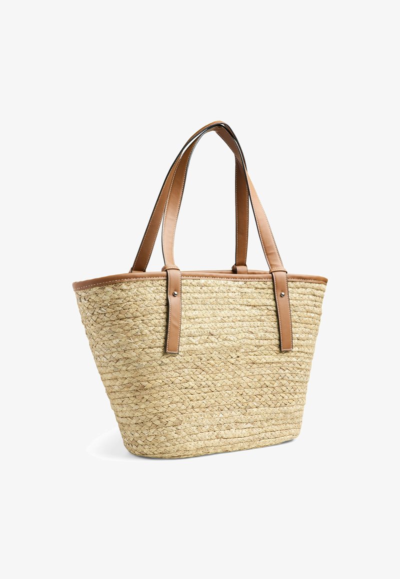 Sac en paille avec deux anses en cuir marron et une bordure en cuir marron. Texture tissée, large ouverture et fond effilé.