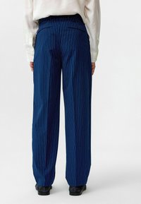 Navyblauwe pinstripebroek met een wijdere pijp, elastische tailleband en zakken aan de achterkant. Gemaakt van een gladde, lichte stof.