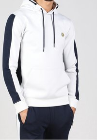 Felpa con cappuccio bianca, maniche blu navy e tasca frontale. Presenta stringhe di colore abbinato e un logo circolare sul petto.