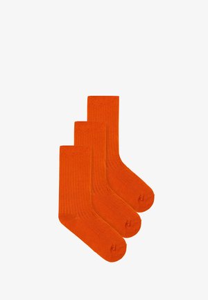 Trzy pary pomarańczowych skarpetek w prążki. Wykonane z miękkiego materiału, cechujące się gładką strukturą i wzmocnionym palcem dla większej trwałości.