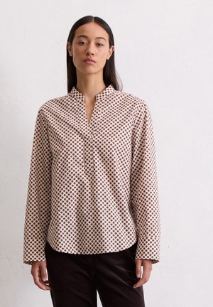 Chemise à manches longues avec col en tissu rose clair, présentant un motif géométrique marron et une patte de boutonnage à moitié. Texture lisse, coupe décontractée.