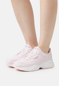Baskets de sport rose clair avec une tige en cuir lisse, une semelle intermédiaire blanche, des perforations pour la respirabilité et des lacets pour un maintien sécurisé.