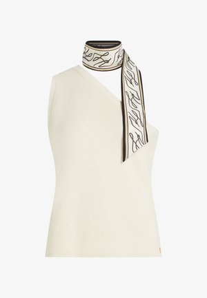 Crèmekleurige off-shoulder mouwloze top met een wit-zwart patroon sjaal gestrikt rond de halslijn.