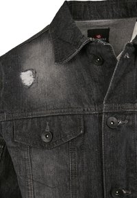 Juodas džinsinis švarkas su nusidėvėjusia tekstūra, užtrauktukais ir dviem krūtinės kišenėmis. Apykaklė ir medžiaga šiek tiek išblukusios.