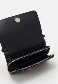 Czarny skórzany portfel z zamknięciem na zamek błyskawiczny, złotymi okuciami, wieloma przegródkami na karty i gładką fakturą. Otwarty, aby pokazać wnętrze z przegródkami.