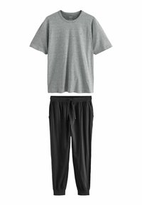 Grå kortærmet t-shirt med rund halsudskæring, parret med sorte joggerbukser med elastisk talje og ankelsnit.