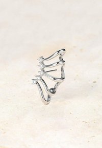 Silberring mit geschwungenem Design, das fünf klare Edelsteine enthält. Der Ring hat eine glatte Oberfläche und eine einzigartige, fließende Form.