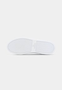 Sole de calçado branca com padrão de espinha de peixe. Material de borracha lisa, apresentando um logótipo ao centro. Biqueira arredondada e design plano.