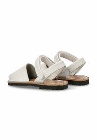 Sandalias de cuero blancas con suela plana, diseño de punta triangular y correas entrelazadas. Presentan un interior texturizado y una plantilla marrón.